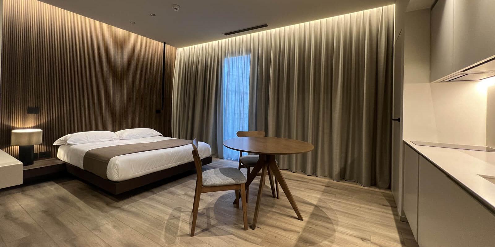 Camera da letto moderna con letto, tavolo rotondo e lampade eleganti.