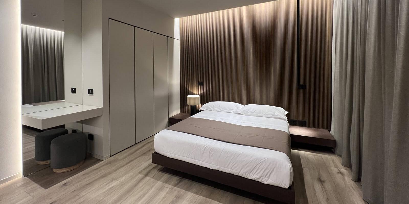 Modern room with double bed, wooden walls, and parquet flooring.