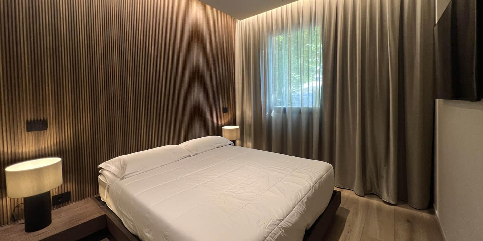 Camera da letto moderna con parete in legno, letto matrimoniale e lampade da comodino.