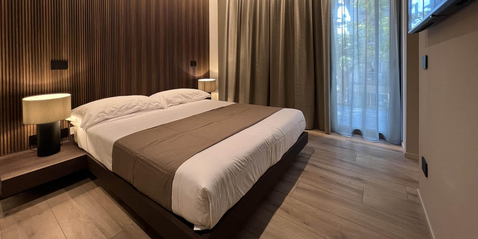 Modern room with double bed, wooden wall, and soft lighting.