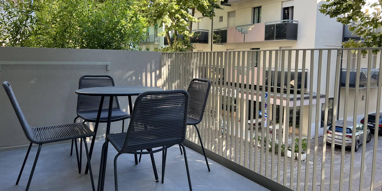 Terrace with table and chairs, view of buildings and trees.